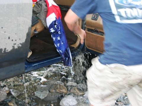 1985 Ford Bronco - Water is being removed from the interior of a vehicle, with an American flag hanging from the open door.