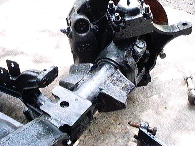 Close-up of a black painted front axle assembly with U-joints and suspension components