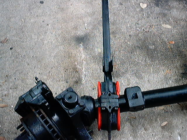 Black steering linkage with red bushings on concrete