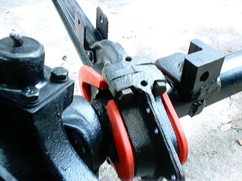 1979 Ford Bronco - This image shows a close-up view of a vehicle's suspension system, focusing on a metal part with red rubber bushings.