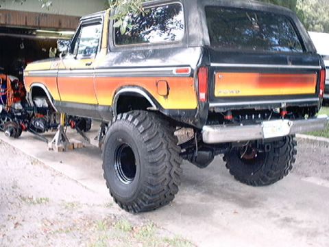 1979 Ford Bronco - Ford Bronco on jack stands with oversized tires, undergoing modifications.