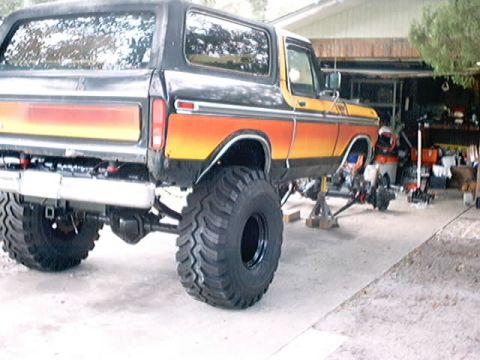 1979 Ford Bronco - This lifted Ford Bronco is undergoing maintenance with its front axle removed and the vehicle supported by jack stands.