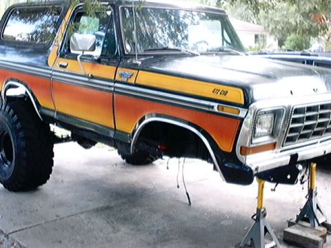 1979 Ford Bronco - This 1979 Ford Bronco features a distinctive orange and yellow stripe pattern and is currently elevated on jack stands.