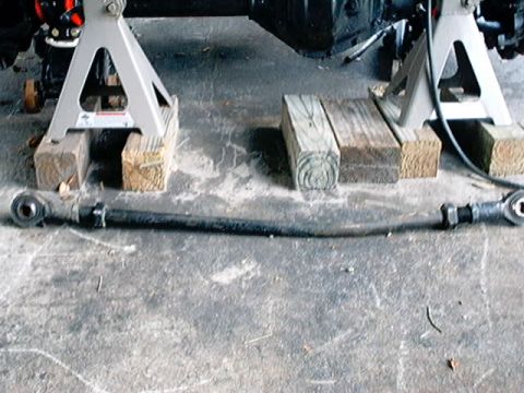 1979 Ford Bronco - A vehicle's tie rod assembly is supported by jack stands and wooden blocks on a concrete floor.