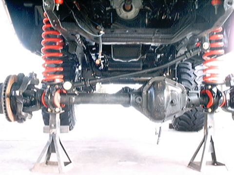 1979 Ford Bronco - The underside of a vehicle is shown, with focus on the rear axle and suspension system.