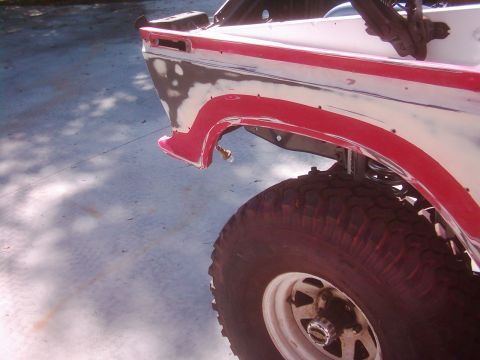 1978 Ford Bronco - The rear quarter panel of a 1978 Ford Bronco shows primer and red trim, indicating bodywork in progress.