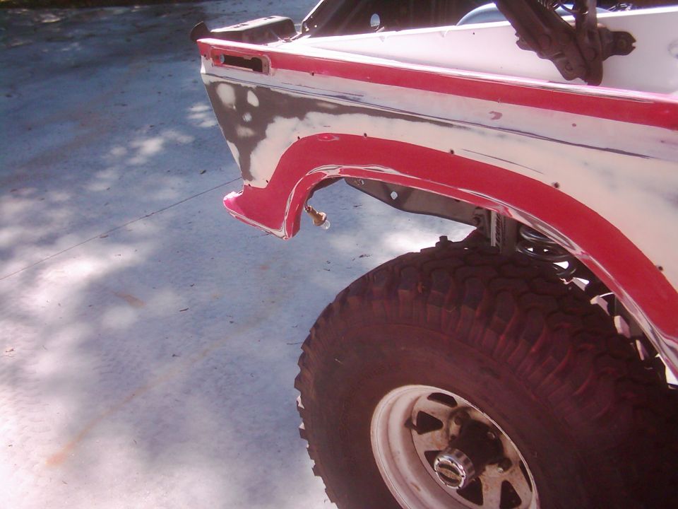 1978 Ford Bronco rear quarter panel with red trim, primer, and exposed metal