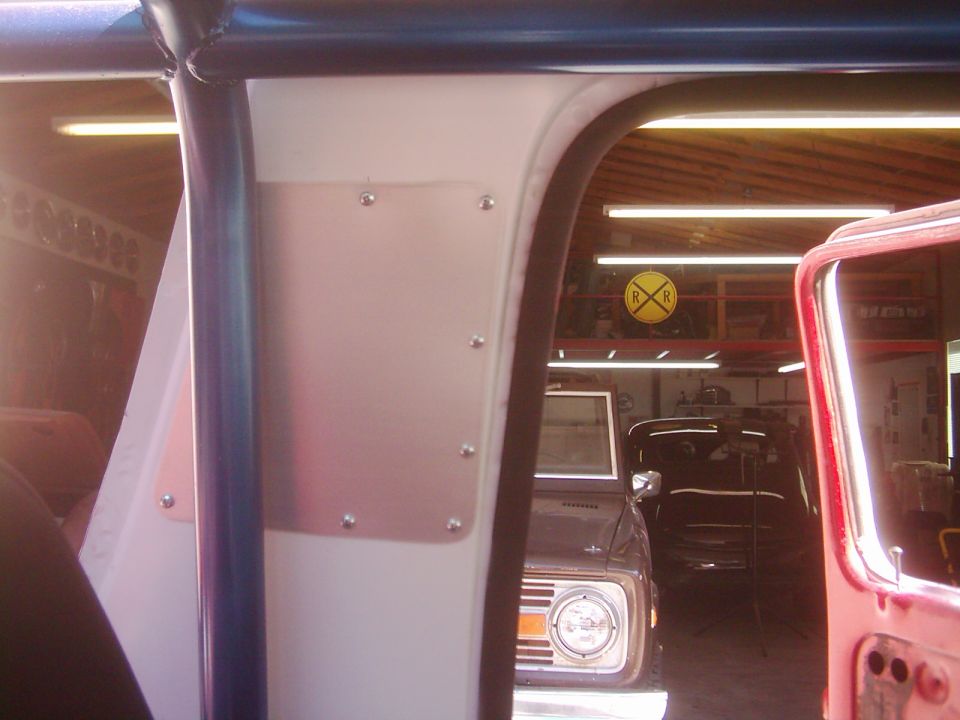 Interior view of a vehicle, looking out through an opening at another vehicle in a garage. A railroad crossing sign is visible on the wall