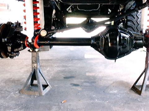 1979 Ford Bronco - Vehicle's front axle and suspension components are visible, supported by jack stands.