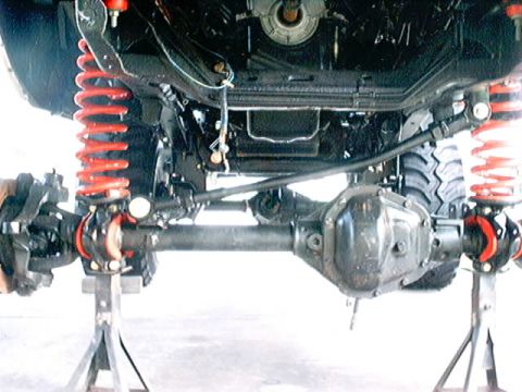 1979 Ford Bronco - The vehicle's suspension system, including the front axle and differential, is visible while elevated on jack stands.