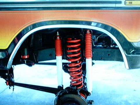 1979 Ford Bronco - The suspension system of a vehicle, bright red coil springs and shock absorbers, is shown in detail.