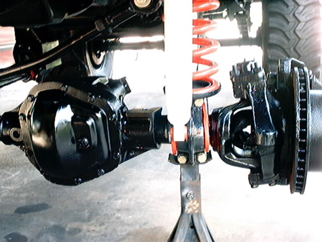Close-up of vehicle differential and suspension parts, including a shock absorber and coil spring