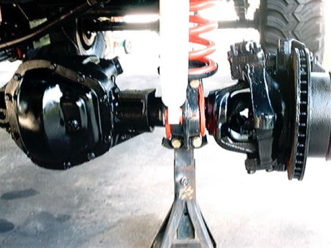 1979 Ford Bronco - The image shows the underside of a vehicle, focusing on the axle and suspension system with a red coil spring visible.