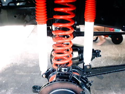 1979 Ford Bronco - Close-up view of the front suspension system, bright red coil springs and white shock absorbers.