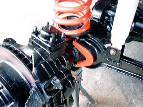 1979 Ford Bronco - Close-up view of a vehicle's front suspension system, highlighting the coil spring and brake components.