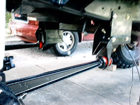 1979 Ford Bronco - Close-up view of a vehicle's suspension component, with another vehicle in the background.