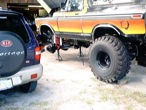 1979 Ford Bronco - This lifted 1979 Ford Bronco, a distinctive orange and yellow stripe, is undergoing service with its hood open.