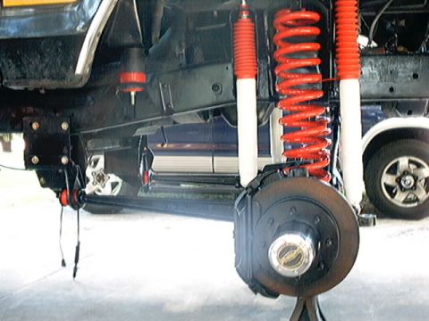 1979 Ford Bronco - Close-up view of the suspension system and undercarriage of a vehicle, with visible brake components and shock absorbers.