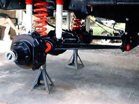 1979 Ford Bronco - Vehicle's front suspension components, including springs and shocks, are supported by jack stands.
