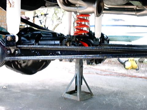 1979 Ford Bronco - Close-up of a vehicle's undercarriage, showing suspension components and a jack stand supporting the frame. The Supermotors.net logo is pre…