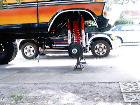1979 Ford Bronco - A lifted Ford Bronco with custom suspension is shown on jack stands, with another vehicle positioned below it.