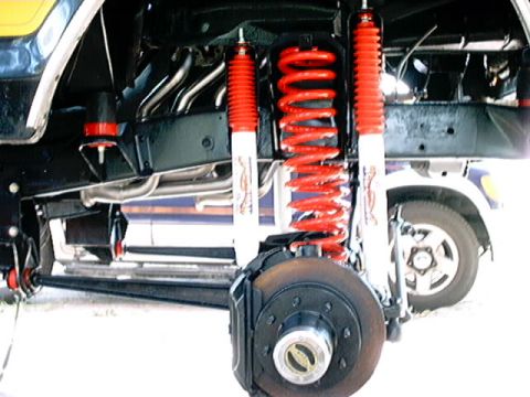 1979 Ford Bronco - This image shows the suspension and brake components of a vehicle, with another vehicle visible in the background.