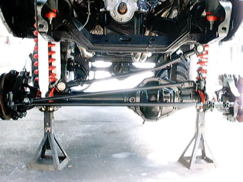 1979 Ford Bronco - The vehicle's undercarriage is visible, supported by jack stands, revealing its suspension and drivetrain.