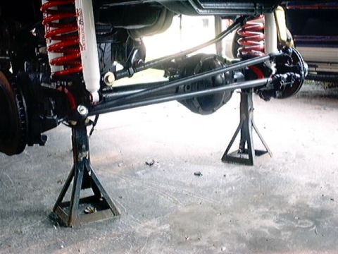 1979 Ford Bronco - Vehicle's front axle and suspension system are elevated on jack stands for maintenance or modification.