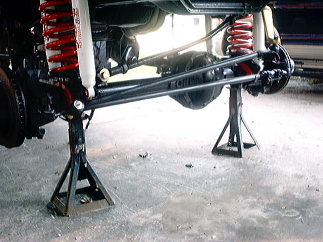 Front axle and suspension on jack stands, red coil springs, white shocks