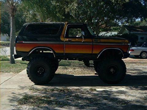 1979 Ford Bronco - This lifted 1979 Ford Bronco features a distinctive two-tone paint scheme with orange and yellow stripes along its side.