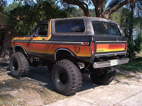 1979 Ford Bronco - This lifted Ford Bronco features a distinctive orange and black gradient paint job and aggressive off-road tires.