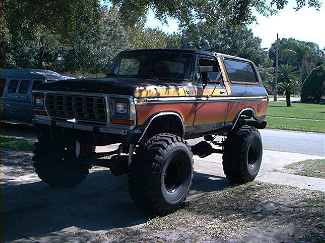 Lifted 1979 Ford Bronco with orange and yellow stripes, large off-road tires
