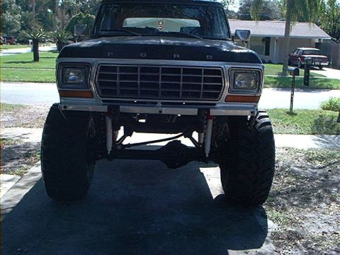 1979 Ford Bronco - This lifted Ford truck features a distinctive grille and is parked in a driveway with a house in the background.