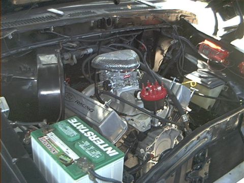 1979 Ford Bronco - View of a V8 engine bay a chrome air cleaner, red distributor cap, and an Interstate battery.