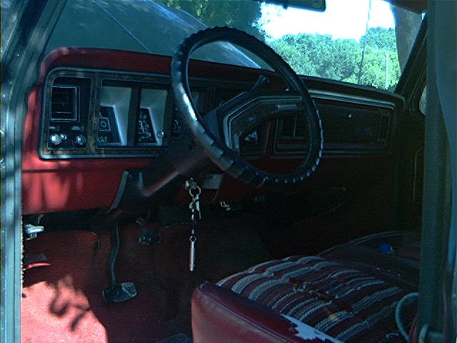 1979 Ford Bronco interior showing dashboard, steering wheel, and striped seat