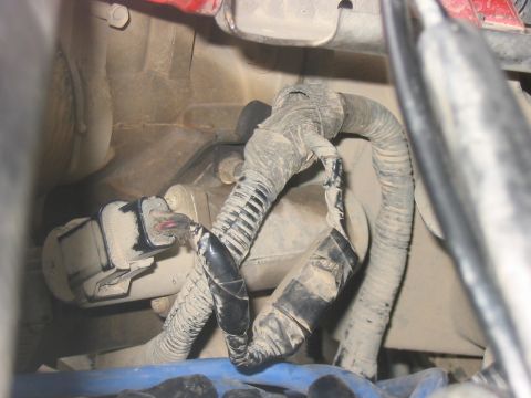 1988 Ford Bronco - Close-up view of a vehicle's engine wiring harness showing frayed and taped sections.