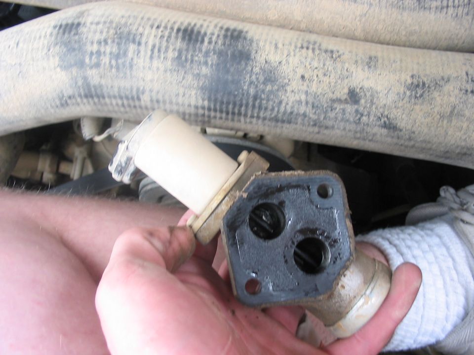 hand holding a dirty automotive part with two circular openings