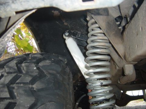 1979 Ford Bronco - Close-up view of a vehicle's suspension system, including a large tire and coil spring.