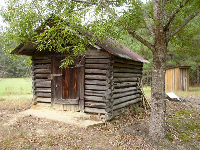 Log cabin with wooden door and outhouse in background