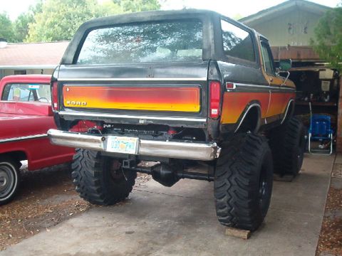 1979 Ford Bronco - This lifted Ford Bronco features a distinctive orange and yellow striped tailgate and large off-road tires.