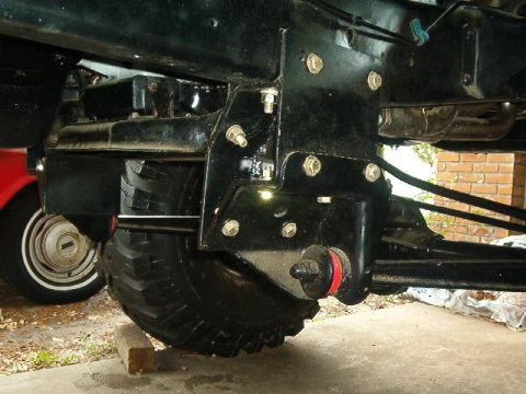 1979 Ford Bronco - Close-up view of a vehicle's suspension system and tire, with another vehicle partially visible in the background.