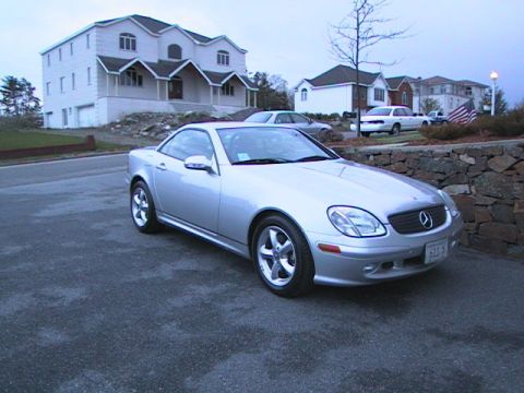 2000 Jeep Liberty - A silver convertible is parked in a driveway in front of a large house. Another car is visible in the background.