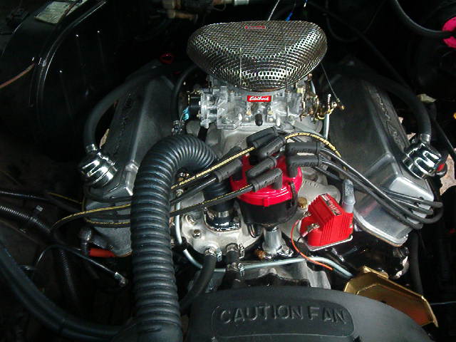 Close-up of a V8 engine with a chrome air cleaner, red distributor cap, and Holley carburetor