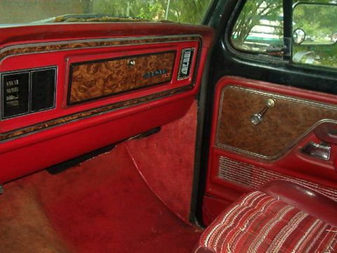 1979 Ford Bronco - The interior of a 1979 Ford Bronco XLT features red upholstery and distinctive woodgrain trim on the dashboard and door panels.