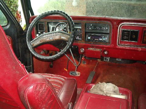 1979 Ford Bronco - The interior of a 1979 Ford Bronco shows red upholstery and a dashboard with an aftermarket stereo.