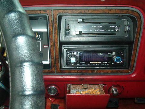 1979 Ford Bronco - Interior view of a car dashboard, showing climate controls, an aftermarket stereo, and an open ashtray.