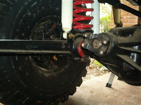 1979 Ford Bronco - Rear axle and suspension detail, showing a red coil spring and white shock absorber.