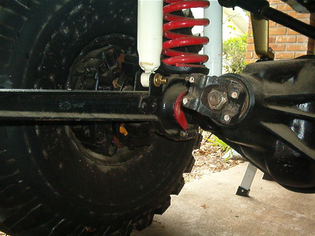 Close-up of a vehicle's rear axle, shock absorber, and coil spring