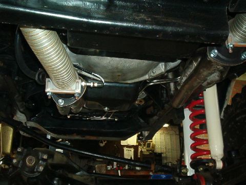 1979 Ford Bronco - The undercarriage of a vehicle is visible, exhaust components and suspension parts.