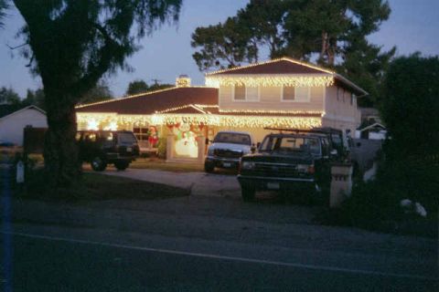 1988 Ford Bronco - A house decorated for Christmas with three SUVs parked in the driveway at dusk.